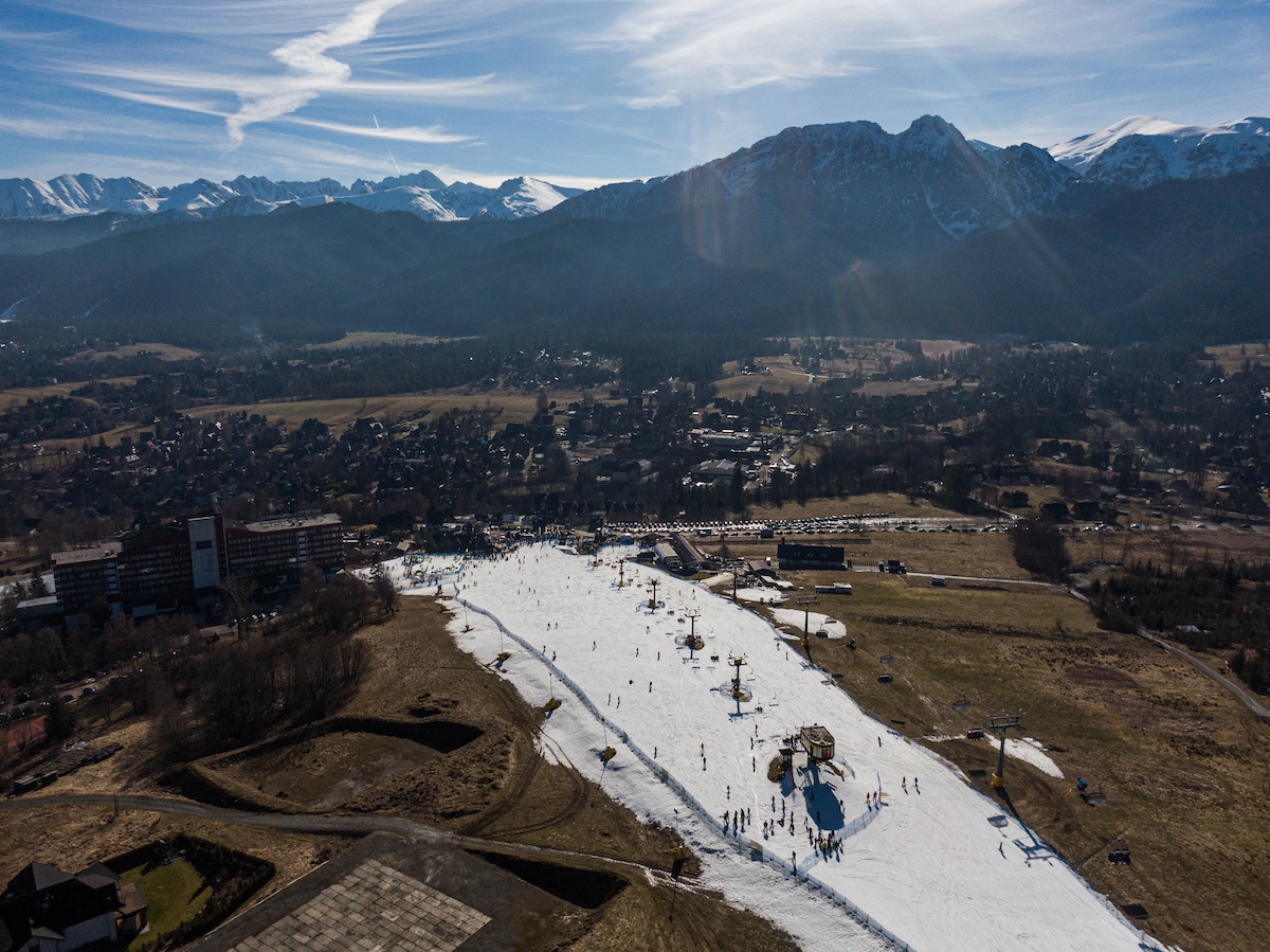 Aerial view of a ski slope operating with a small amount of snow during an unusually high temperature day in Zakopane, Poland